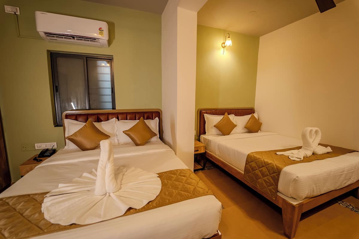 Two neatly made beds with towels, a bedside phone, and a wall-mounted air conditioner.