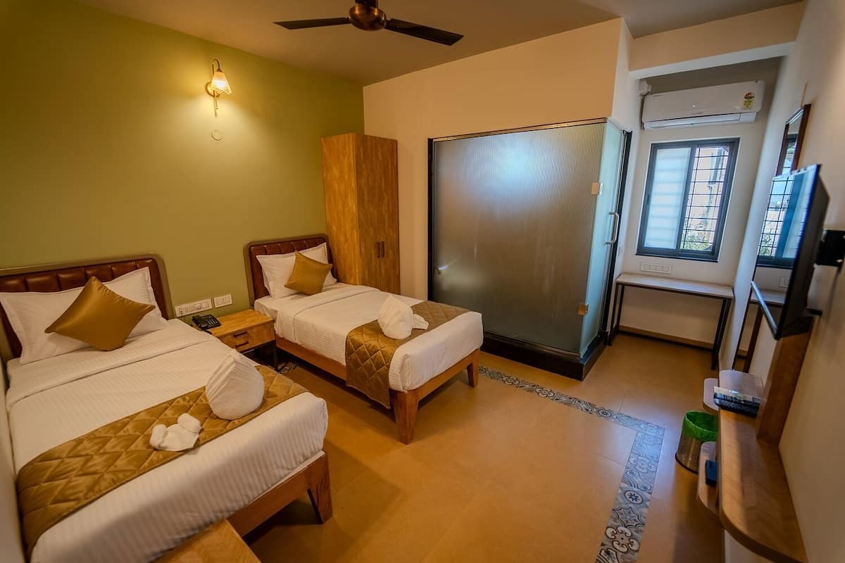A hotel room with two beds, a wardrobe, a desk, a television, and a sliding door.