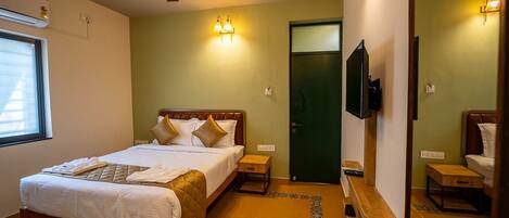 Ein Hotelzimmer mit einem Bett, einem Deckenventilator, einem Fernseher und einer grünen Tür.