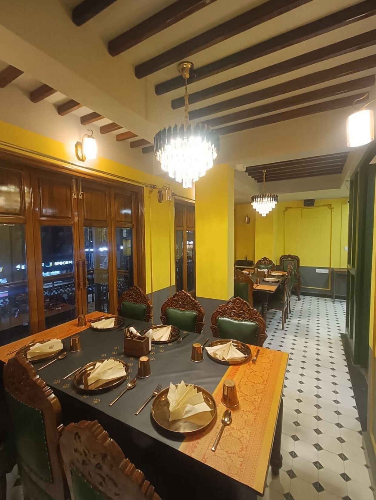 Un comedor con una mesa larga dispuesta para varias personas, sillas de madera y una lámpara de araña.