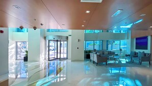 Un'ampia hall con una porta girevole in vetro, un'area salotto con divani e ampie finestre che lasciano entrare luce naturale.