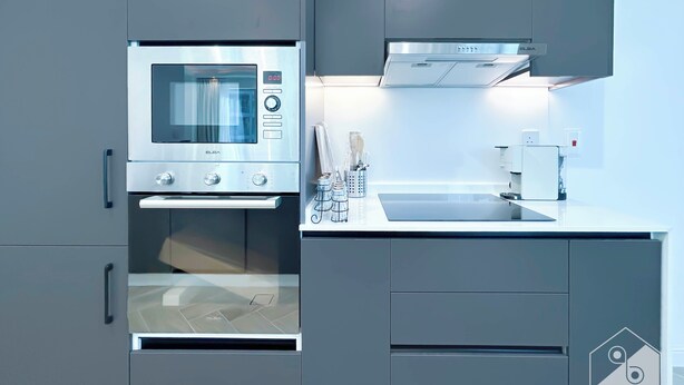 Una cucina moderna con forno a microonde, forno e macchina del caffè integrati.