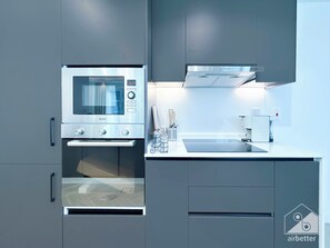 A modern kitchen with a built-in microwave, oven, and coffee maker. - Spacious 2B Apt With Full Marina Views - Delphine (Dubai)