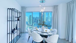 Zona pranzo moderna con vista sulla città, un lampadario e un mobile a scaffali in metallo nero.