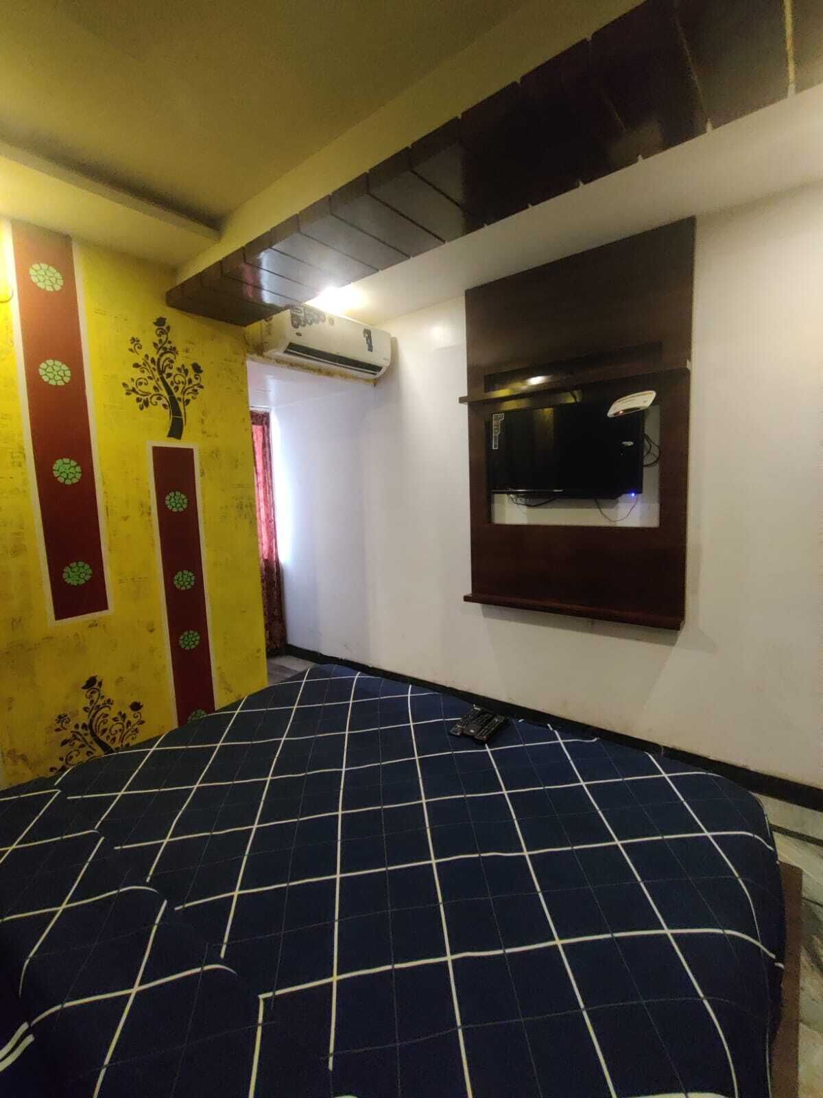 A room with a bed, an air conditioning unit, a window with a mirror, and a wall with decorative patterns.
