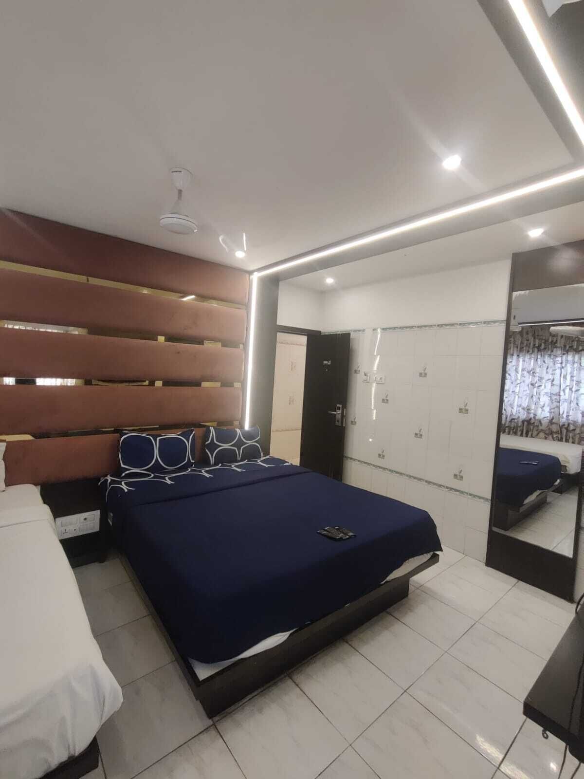 A modern bedroom with a large bed, a bedside table, a wardrobe, and a mirror.