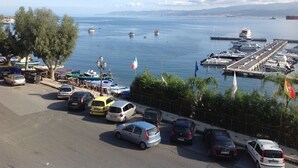 A marina with boats docked, a parking area with cars, and a clear view of the water and distant mountains. - La Casa Di Levante, Charming apartment with panoramic terrace. (Milazzo)