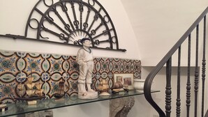 A staircase with a black balustrade, a decorative metal piece above, and a tiled wall with a patterned design. - La Casa Di Levante, Charming apartment with panoramic terrace. (Milazzo)
