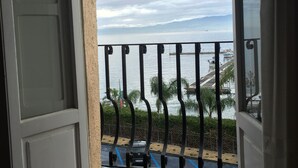 A balcony with a metal railing overlooking a body of water and a distant shoreline. - La Casa Di Levante, Charming apartment with panoramic terrace. (Milazzo)