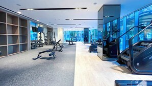 A modern gym with various exercise equipment, a treadmill, and a mirrored wall reflecting the room. - Luxurious 1BR at Grande Downtown With Iconic Views (Dubai)