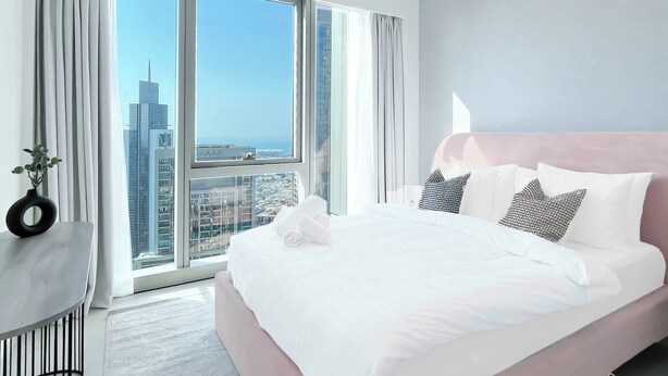 A modern hotel room with a large bed, a view of the cityscape through floor-to-ceiling windows, and a minimalist decor. - Luxurious 1BR at Grande Downtown With Iconic Views (Dubai)