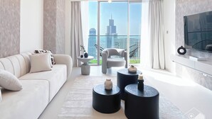 A modern living room with a sofa, two side tables, a chair, and a TV. - Luxurious 1BR at Grande Downtown With Iconic Views (Dubai)