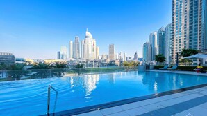 A swimming pool with a city skyline in the background, surrounded by high-rise buildings. - Luxurious 1BR at Grande Downtown With Iconic Views (Dubai)