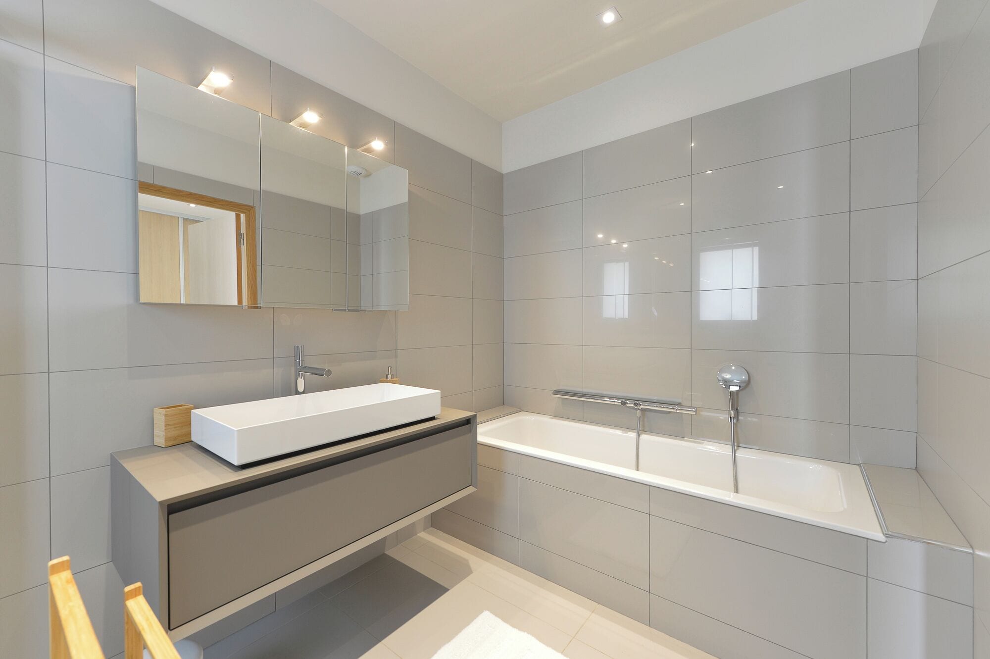 A modern bathroom with a large mirror, a white sink, and a freestanding bathtub.