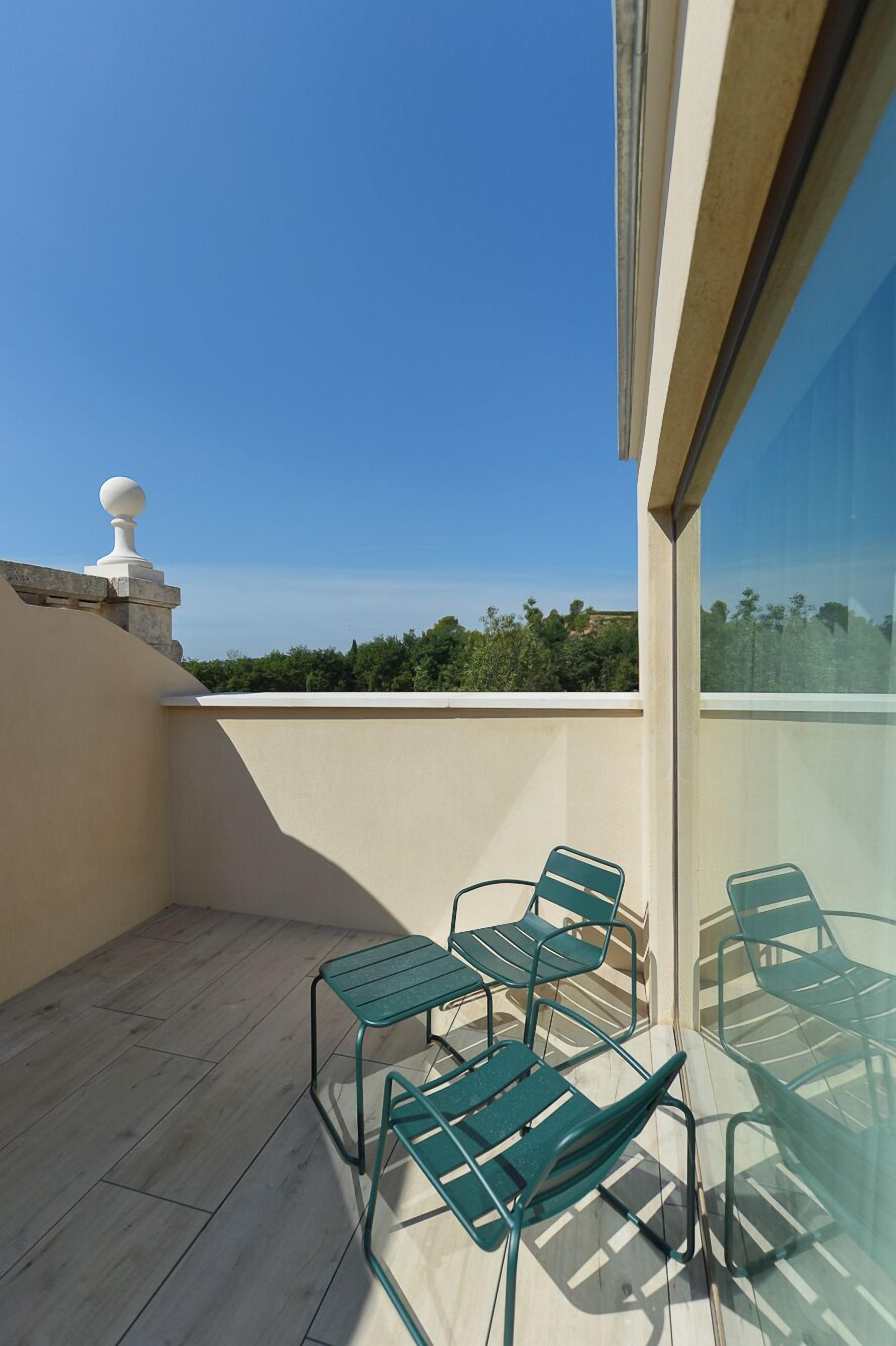 A balcony with four green metal chairs and a white balustrade.