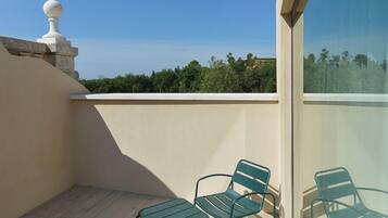 A balcony with four green metal chairs and a white balustrade.