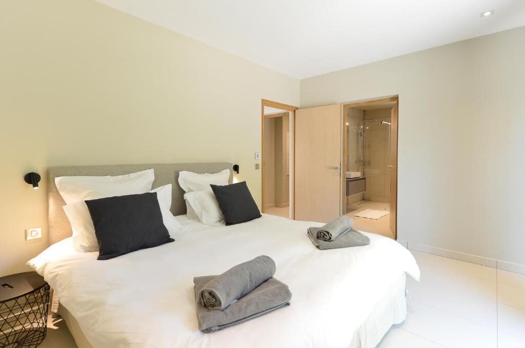 Ein modernes Hotelzimmer mit einem großen Bett, einem Nachttisch und einer großzügigen Dusche.