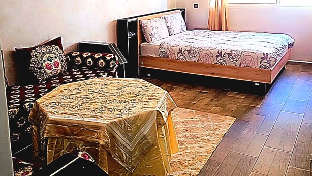 A bedroom with a bed, a small table, and a chair. - Entire private studio with everything you need for a pleasant stay. (Rabat)