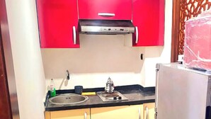 A compact kitchen with red upper cabinets, a stainless steel range hood, a sink with a faucet, and a refrigerator. - Entire private studio with everything you need for a pleasant stay. (Rabat)