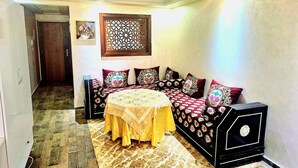 A room with a round table, a sofa with patterned cushions, and a decorative screen on the wall. - Entire private studio with everything you need for a pleasant stay. (Rabat)
