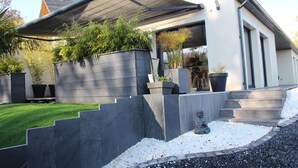 Una casa moderna con un porche cubierto, una escalera de piedra y una estatua en el jardín.