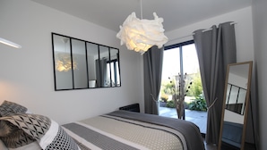 Un dormitorio moderno con una cama grande, una lámpara colgante, un espejo y vistas al exterior.