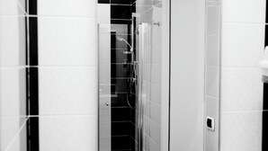 A bathroom with a white sink, a mirror, and black-tiled walls. - Casa Vacanze Fardella Centrale (Trapani)