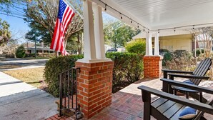 A covered patio with brick pillars, outdoor seating, and an American flag. - The Red Door House in Historic Georgetown (Georgetown)