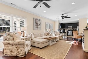 A spacious living room with a sectional sofa, a coffee table, and a large window with blinds. - The Red Door House in Historic Georgetown (Georgetown)