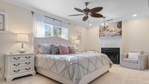 A bedroom with a large bed, a ceiling fan, a fireplace, and a window with curtains. - The Red Door House in Historic Georgetown (Georgetown)
