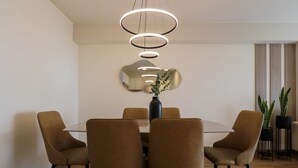 A modern dining area with a glass table, four chairs, a vase with flowers, a mirror, and a hanging light fixture. - w* | Pleasant 3BR w/ Balcony in San Isidro (Lima)