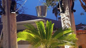 Una pianta in vaso con base in pietra, un arco decorativo in metallo e un cielo sereno.