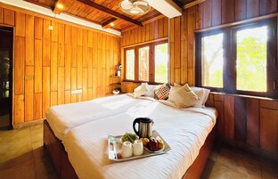 A wooden-paneled bedroom with a bed, pillows, a tray of fruits, and a pitcher.