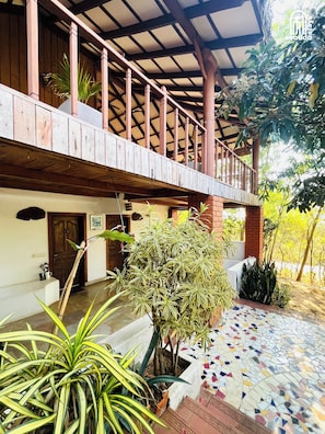 A covered outdoor area with a wooden balcony, potted plants, and a tiled floor. - The Hideaway Hosur by evaddo stays (Hosur)