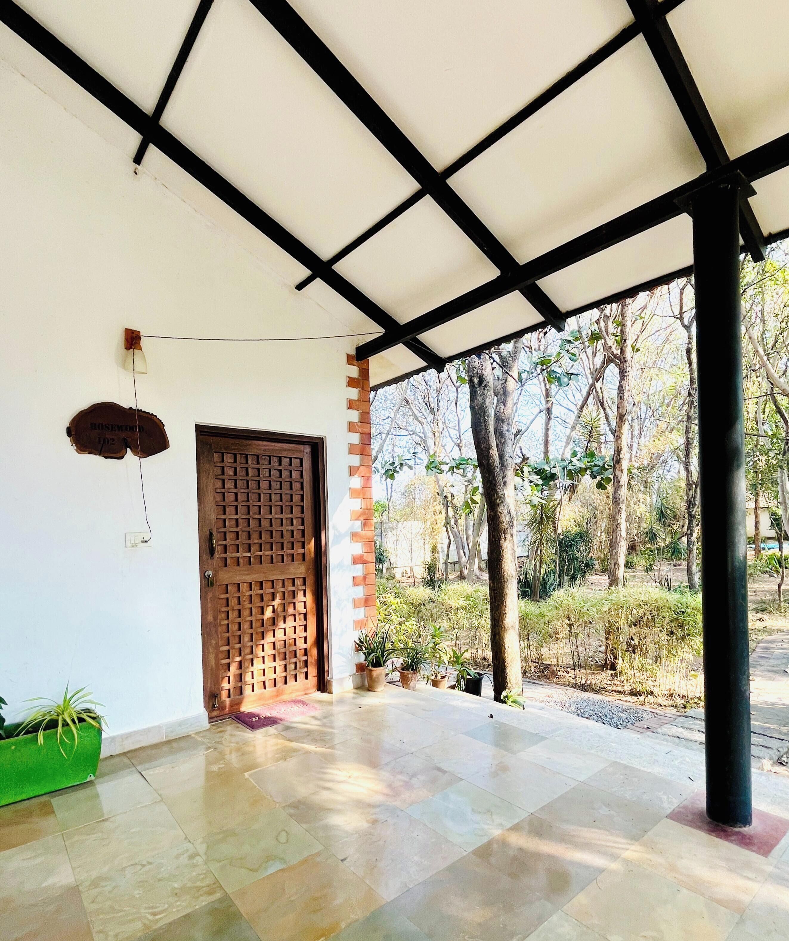 A covered porch with a tiled floor, a wooden door, and a brick wall.