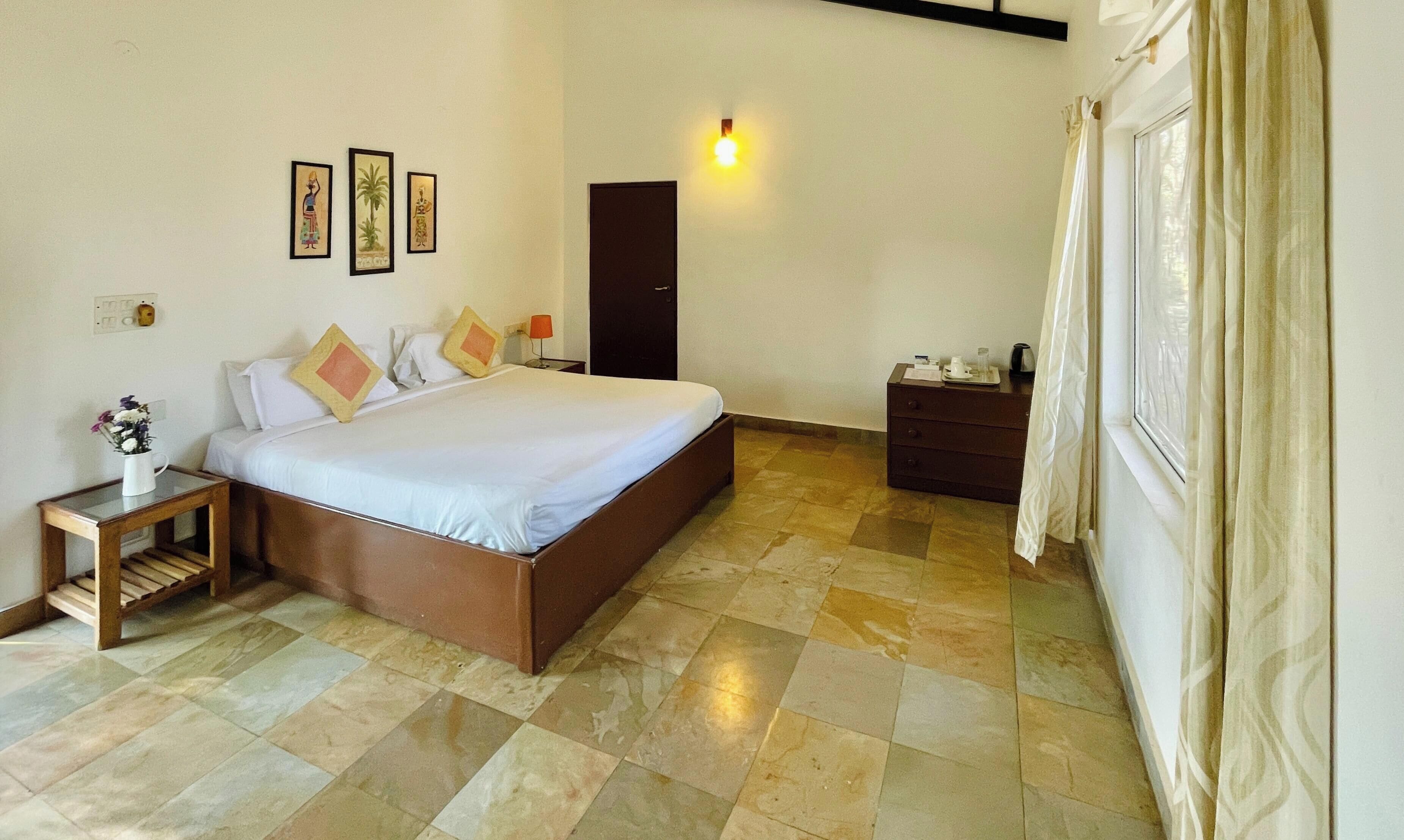A hotel room with a bed, bedside table, lamp, and a dresser.