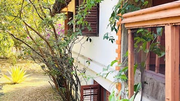 A traditional house with a thatched roof, surrounded by lush greenery and flowering plants.