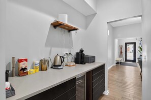 A modern kitchen with a white countertop, black cabinets, and a wooden shelf.