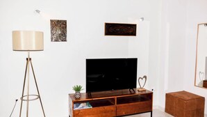 A modern living room with a wooden TV stand, a floor lamp, and artwork on the wall. - Acropolis view (Athens)