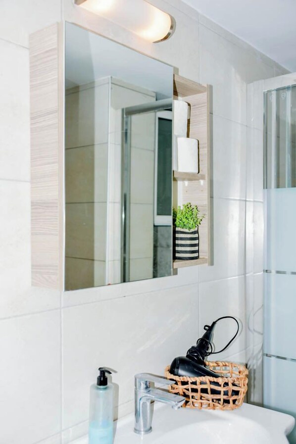 A bathroom with a white sink, a mirror, and a small potted plant. - Acropolis view (Athens)