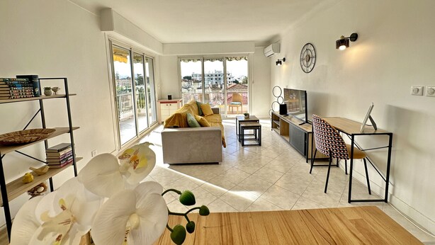 Una sala de estar moderna con sofá, mesa de centro, televisor y un área de comedor con una silla y mesa.