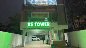 Un edificio de varios pisos con letreros que indican 'Magic Alpha Residency', 'Evo Fitness' y 'BS Tower'.