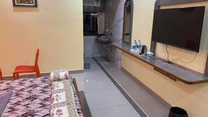 A hotel room with a bed, a TV, a small table with water bottles, and a bathroom visible through an archway. - Magic Alpha Residency (Bhubaneshwar)