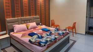 Un dormitorio moderno con cama, almohadas, una mesita de noche y dos sillas.