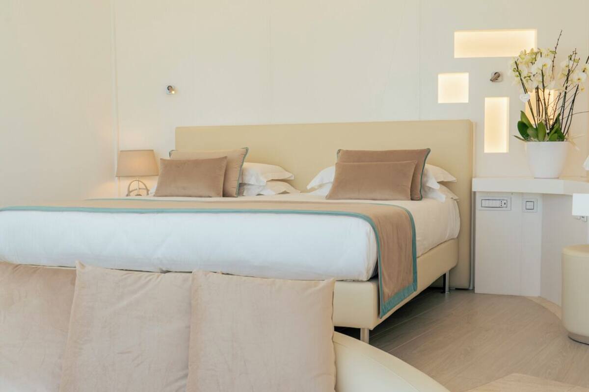 A modern bedroom with a bed, a sofa, and a bedside table.