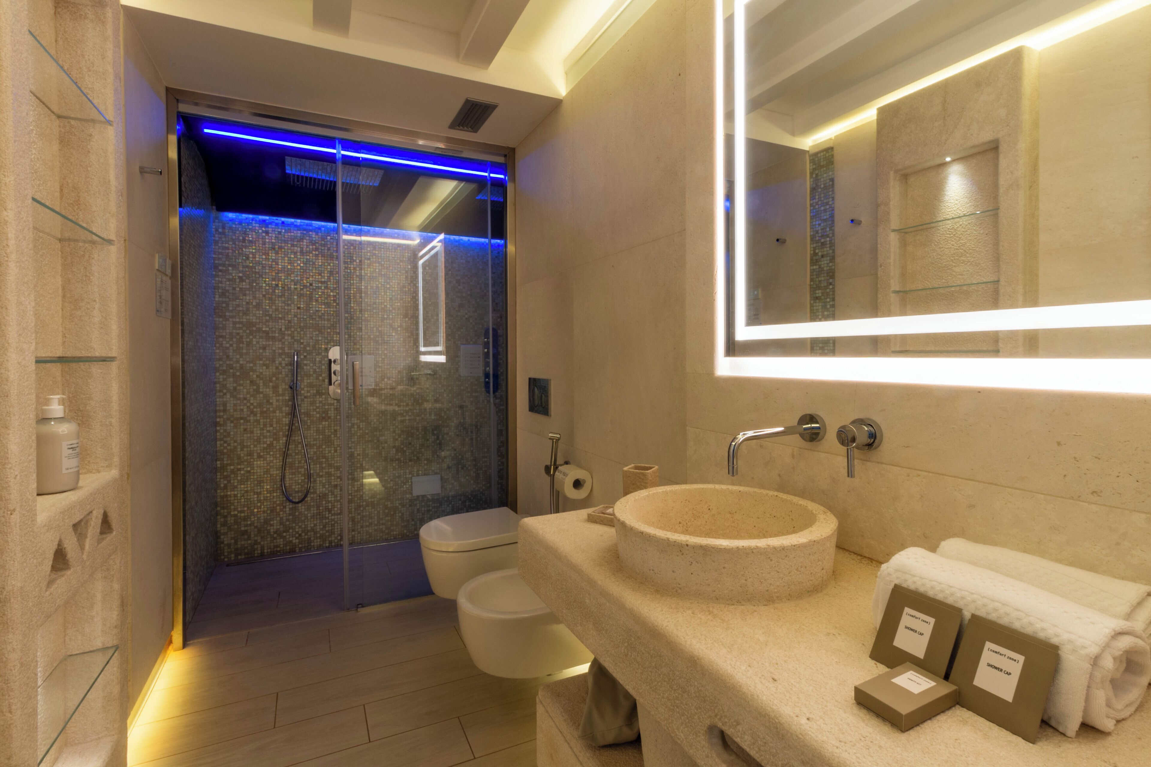 A modern bathroom with a glass-enclosed shower, a round sink, and a large mirror.