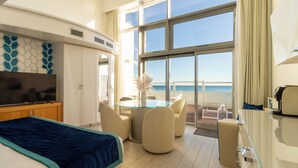 A hotel room with a bed, a TV, a glass table with chairs, and a view of the ocean. - New Bussola (Quartu Sant'Elena)