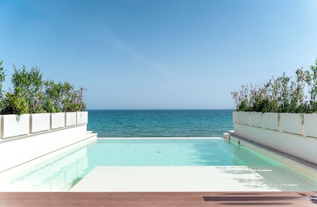 Una piscina al aire libre, sombrillas, sillones reclinables de piscina