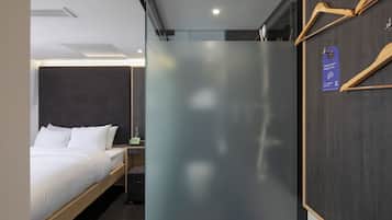 Ein Hotelzimmer mit Bett, Nachttisch, Spiegel und einem Kleiderhaken aus Holz mit einem Etikett.