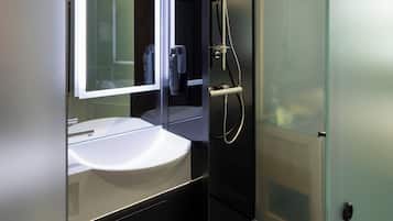 Ein modernes Badezimmer mit einer Glaskabine zur Dusche, einem weißen Waschbecken und einem Spiegel darüber.
